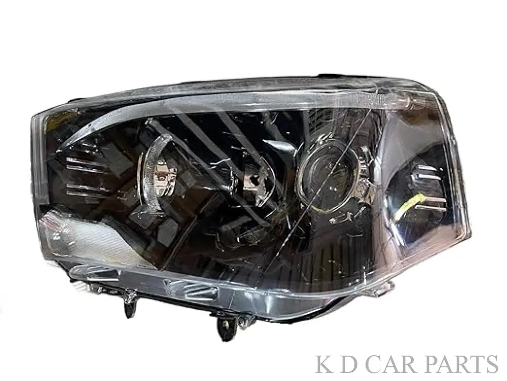 A white projector headlight for the Mahindra Scorpio vehicle, showcasing the front view with clear glass and metal assembly.